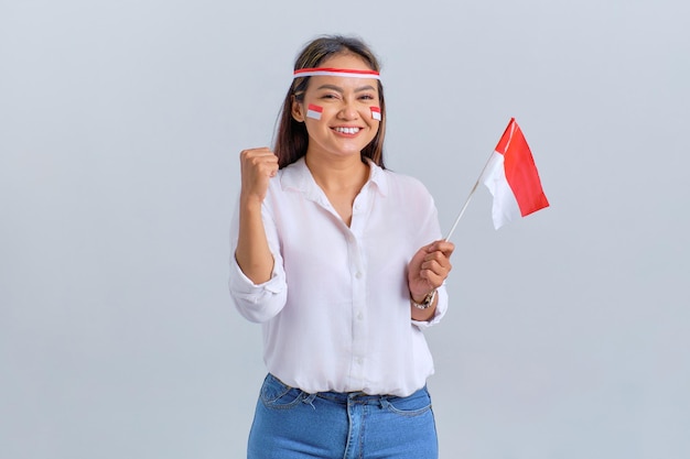 Excited young Asian woman celebrate Indonesian independence day holding the Indonesian flag isolated on white background