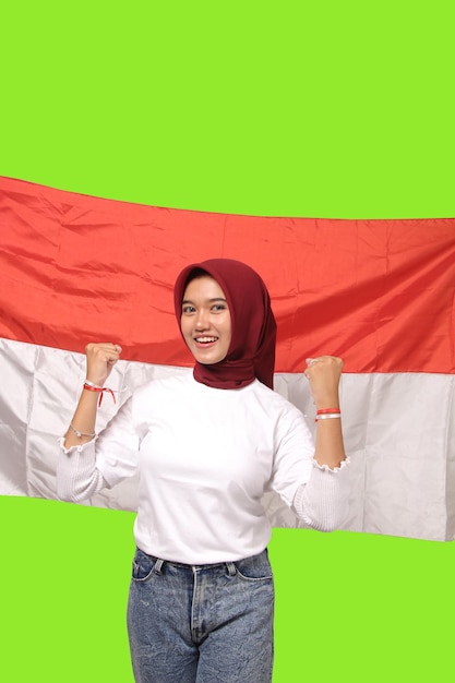 Foto eccitata giovane donna asiatica in hijab che celebra il giorno dell'indipendenza indonesiana isolato sfondo verde