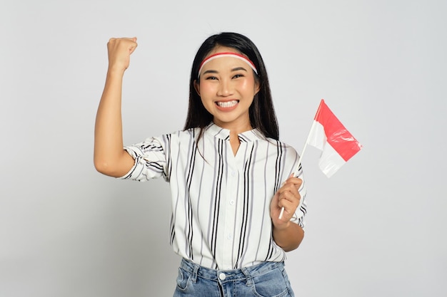 Excited young Asian women celebrate Indonesian independence day holding the Indonesian flag isolated on white background