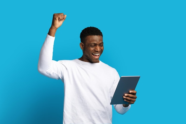 Взволнованный молодой чернокожий мужчина использует цифровую панель и жестикулирует