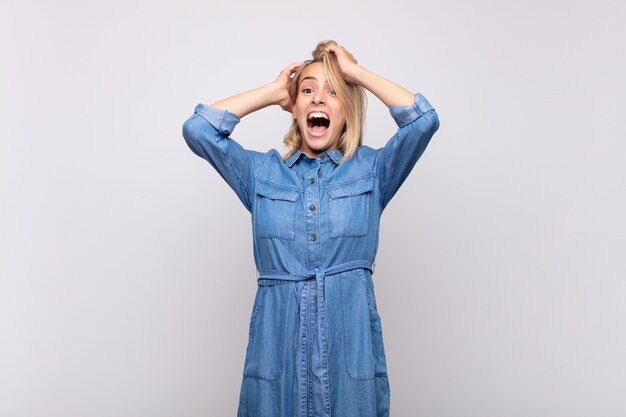 Excited young blonde pretty woman with jean dress