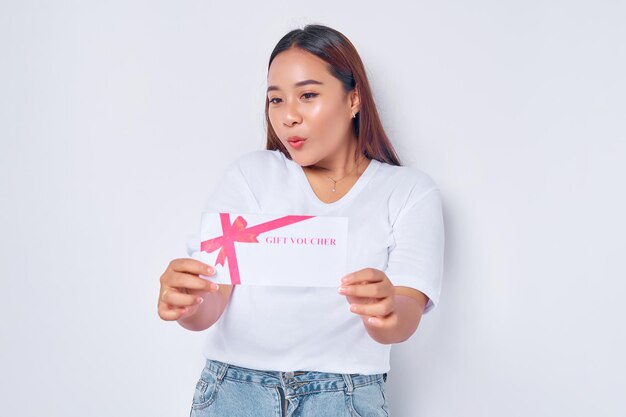 Excited young blonde woman girl Asian wearing casual white tshirt and looking gift certificate coupon voucher in hand isolated on white background People lifestyle concept