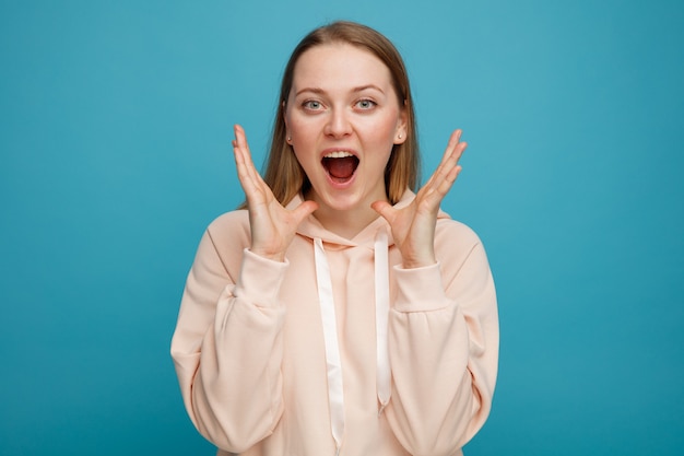 Excited young blonde woman keeping hands near head 