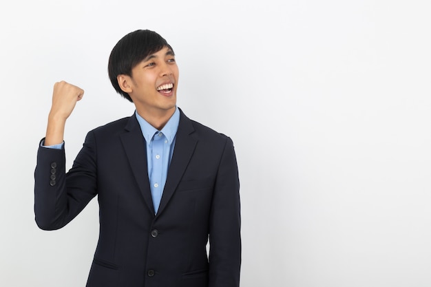 Excited young business Asian man raising his fists with happy delighted face, celebrating success