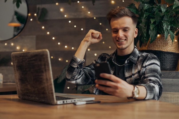 Excited young businessman celebrating successful project and victory while reading good news