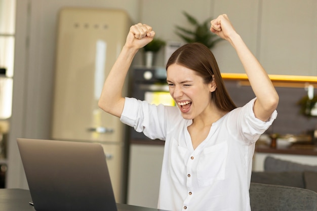 Eccitata giovane donna caucasica che celebra il raggiungimento dell'obiettivo da sogno. una donna d'affari di successo si rallegra dei risultati del progetto finanziario