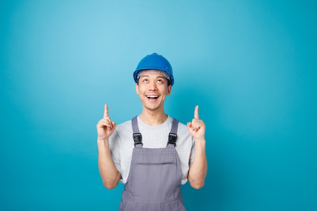 安全ヘルメットと制服を着て見上げて上向きに興奮している若い建設労働者