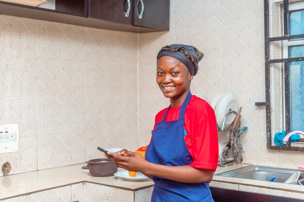 Photo excited young female cook using mobile phone in kitchen