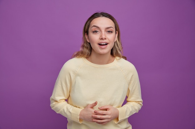 Excited young girl keeping hands on belly 