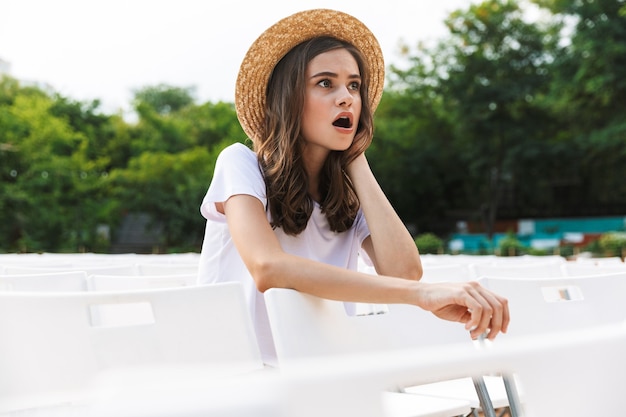 Excited young girl sitting at the city park outdoors in summer