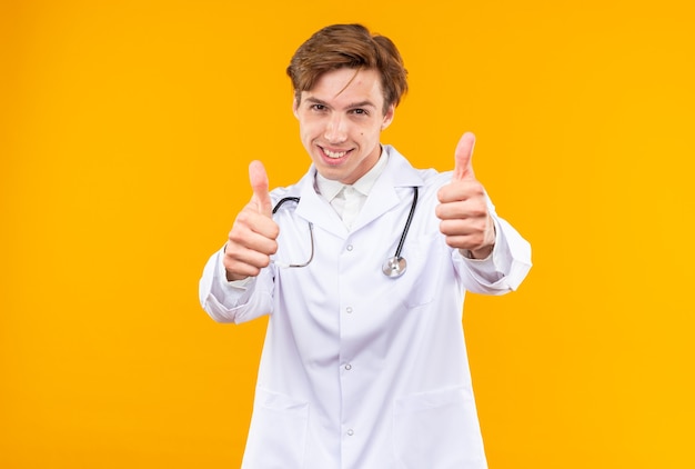 Photo excited young male doctor wearing medical robe with stethoscope showing thumb up