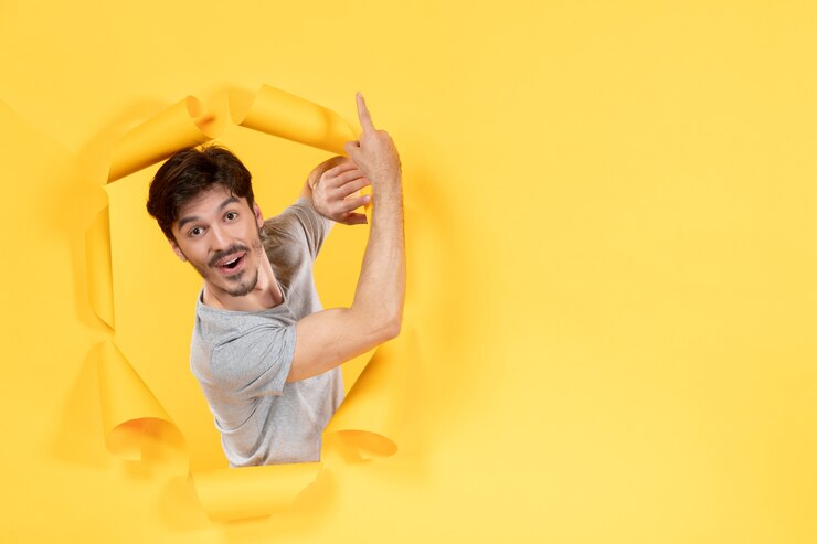 excited young male on torn yellow paper background indoor handsome facial guy