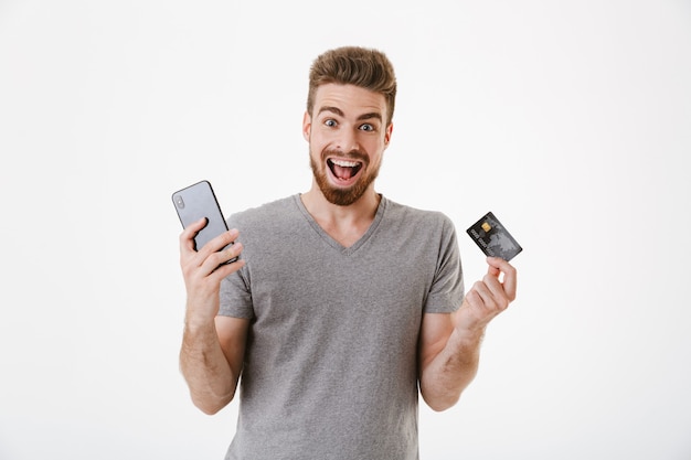 Excited young man holding credit card using mobile phone.