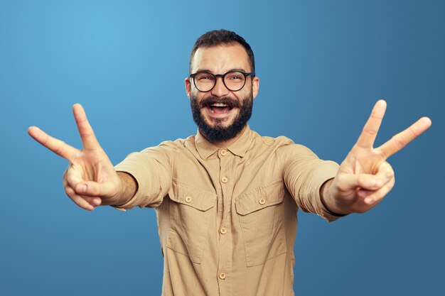 Excited young man screams and showing victory gesture with both hands