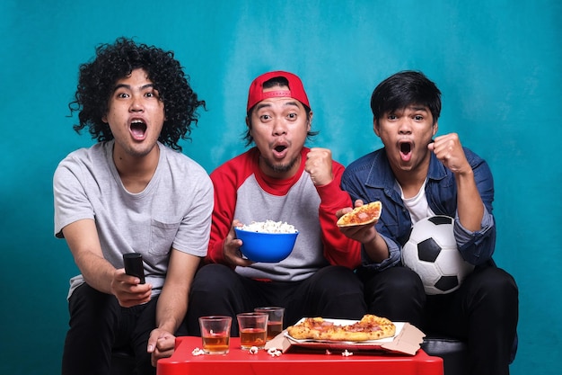 Excited young men friends cheer up supporting favorite football team while screaming doing winner ge