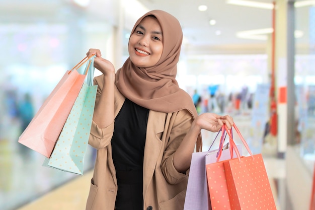 Excited young muslim woman shopping holding paper bag in her hand at the mall