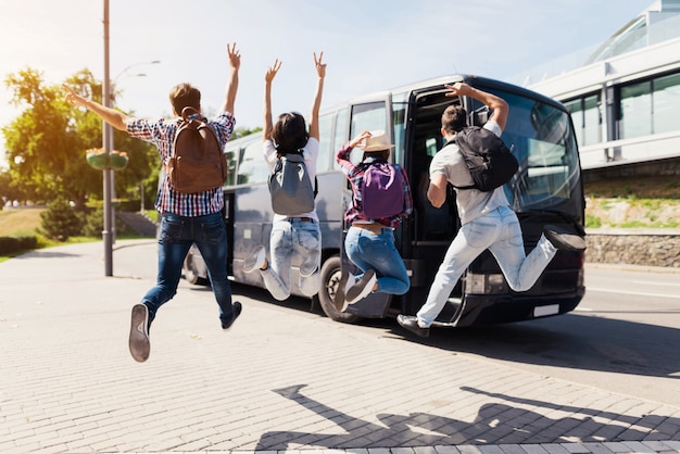 I giovani emozionanti saltano vicino all'autobus di viaggio.