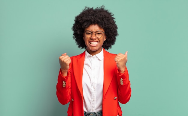 Excited young pretty black woman clenching teeth