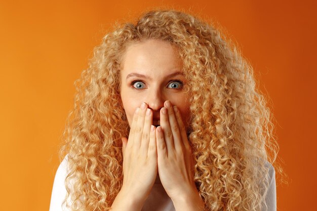 Excited young woman closing mouth with her hand