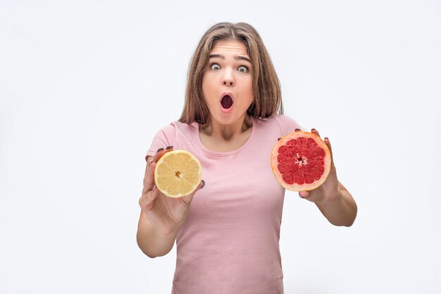 Excited young woman hold half of leman and grapefruit