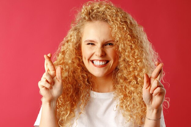 Excited young woman holding crossed fingers for luck