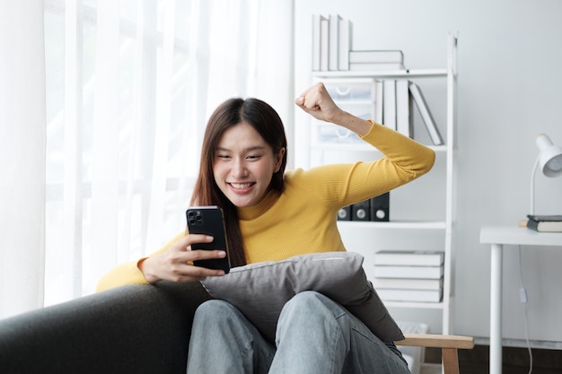 Excited young woman holding phone reading sms with good news or winning online shopping promo