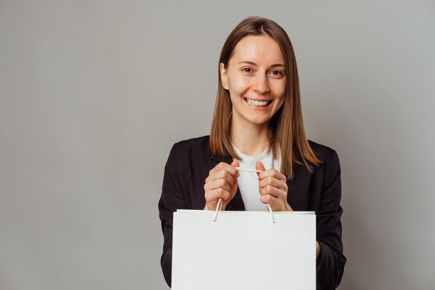 Excited young woman is holding a clean white shopping bag with copy space