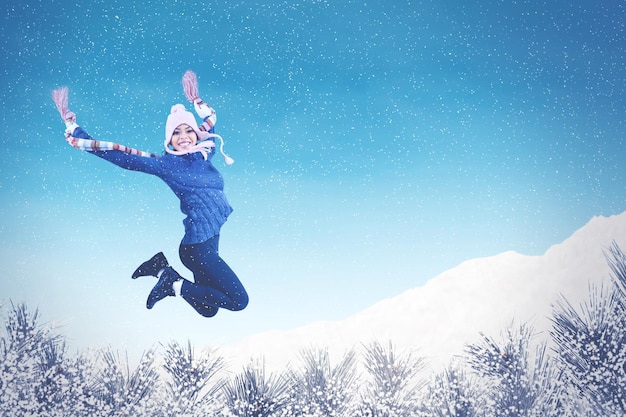 興奮した若い女性が公園で降雪の下でジャンプ