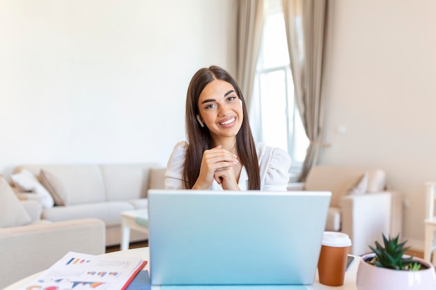 Giovane donna eccitata che guarda la telecamera tenendo una conversazione divertente con i colleghi vista webcam online colpo di testa di giovane donna con le cuffie che ride divertendosi dall'ufficio di casa