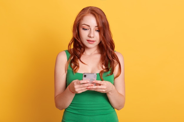 Excited young woman looking at her mobile phone with astonished facial expression