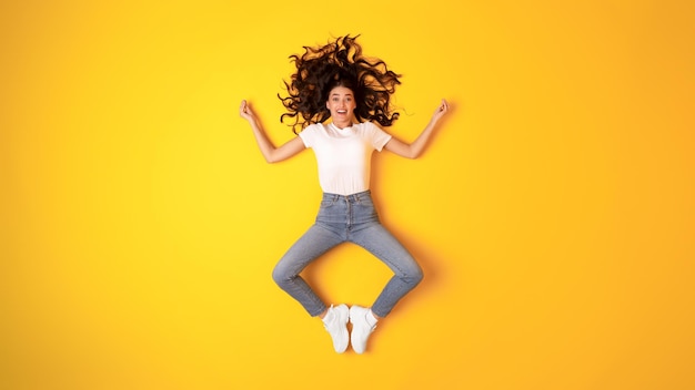 Excited young woman posing making om gesture meditating yellow background