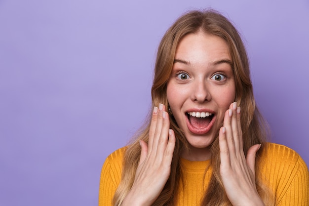 excited young woman smiling and looking at front isolated over blue wall