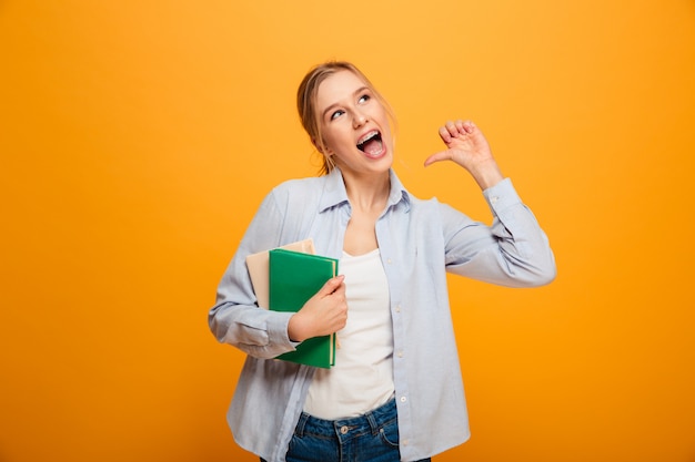 Excited young woman student pointing holding books