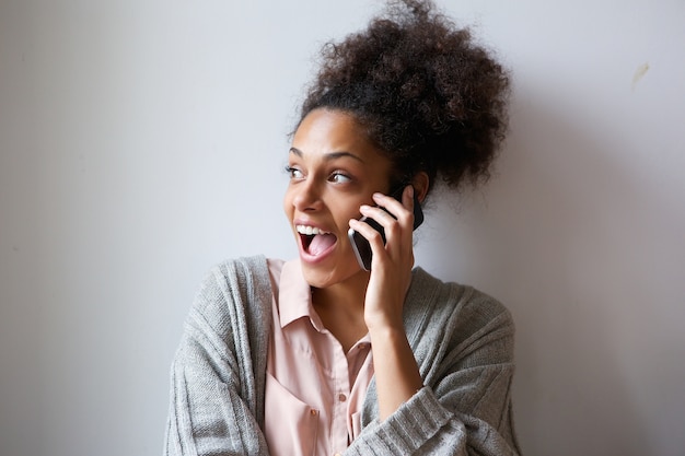 Excited young woman talking on mobile phone