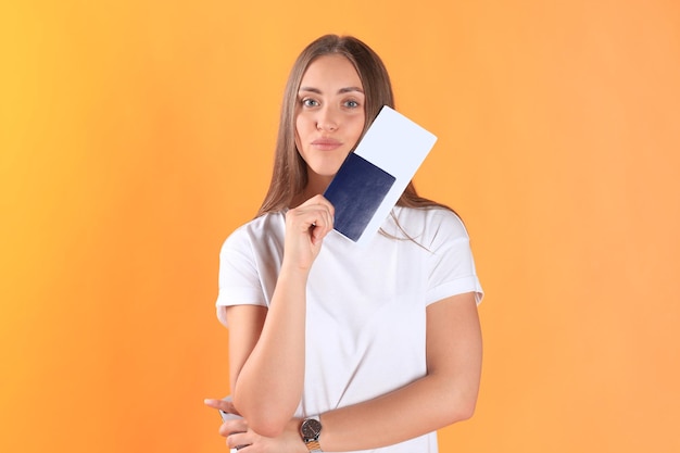 Photo excited young woman tourist standing isolated on yellow background holding passport with tickets, plastic credit card.