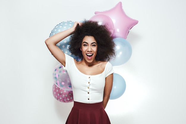 Excitement and happiness surprised young afro american woman holding colourful balloons looking at