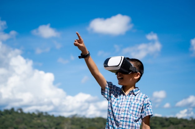 Exciting kids watching virtual reality box or VR box on hills nature background