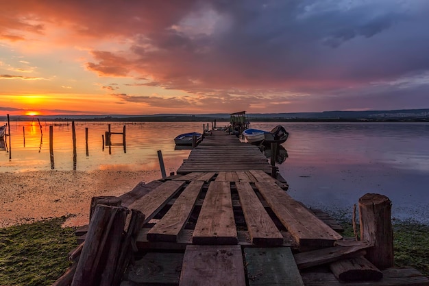 Exciting long exposure landscape on a beach with wooden pier and boats