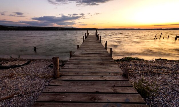 Exciting twilight at the shore with a wooden pier and moored boat