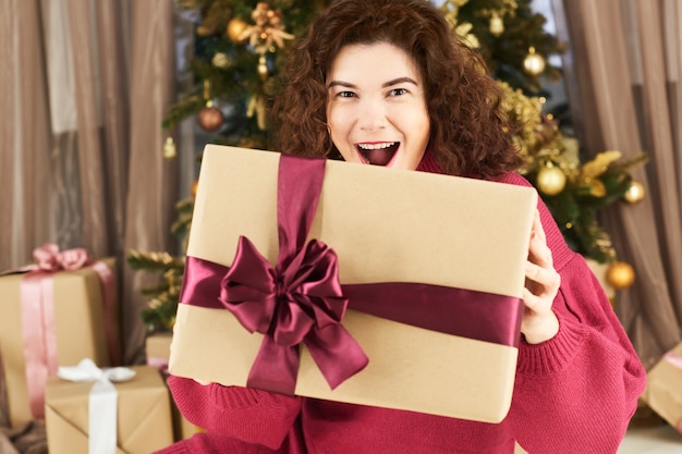 Exciting young woman holding christmas gift box