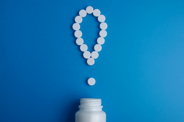 exclamation mark with pills poured from a medicine bottle. Top view. Flat lay.