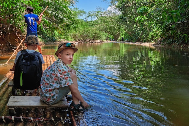 Excursiereis op bamboevlot langs de rivier in de jungle Jongens varen op vlot tropische rivier