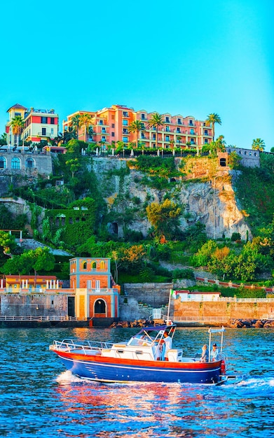 Excursion cruise boat and ship with tourists in luxury Marina Grande port in Sorrento near Naples on Tyrrhenian sea, Amalfi coast, Italy. Italian summer paradise. Mountains on Amalfitana coastline.