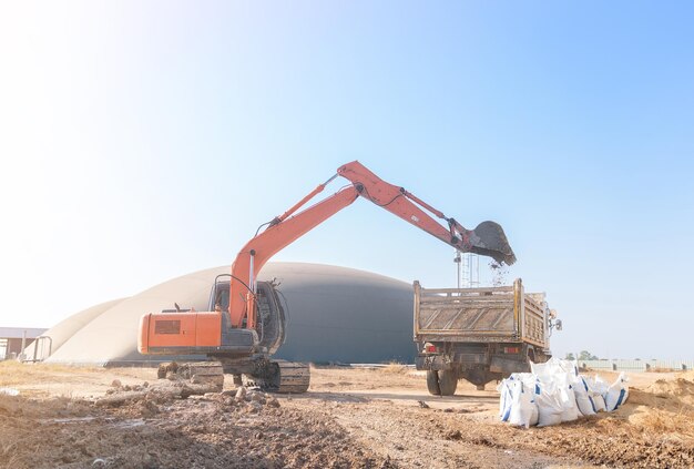 Photo the excuvator digs the topsoil into the dump truck on edge of wastewater threatment ponds