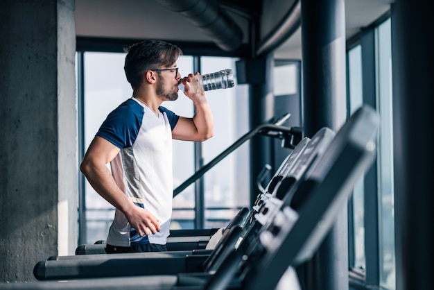 Execising on a treadmill and drinking water.