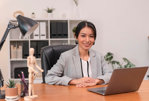 Исполнительная азиатская деловая женщина сидит на столе в офисе