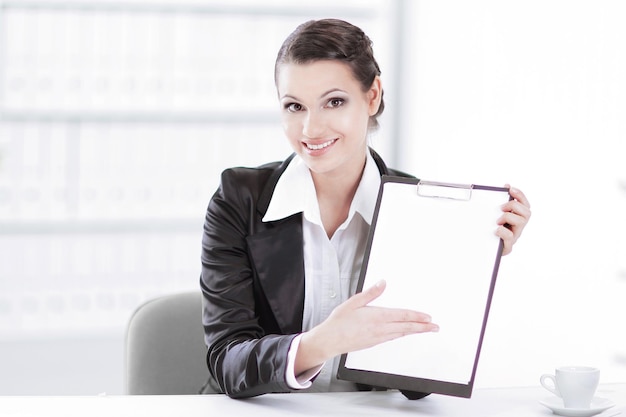 Executive business woman showing blank sheetsitting at her desk