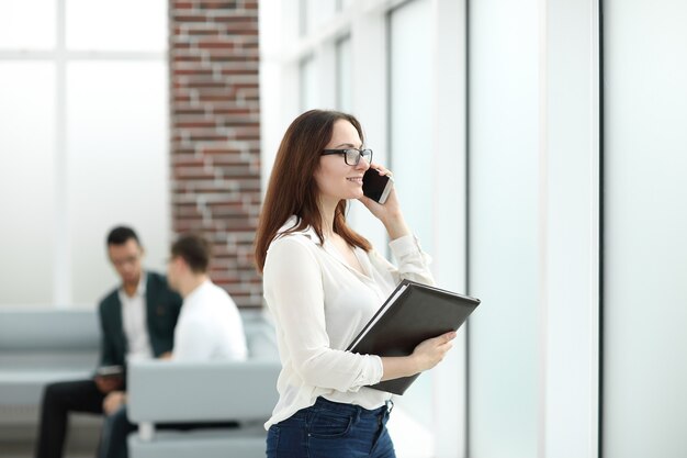 Executive business woman with clipboard talking on mobile phone.