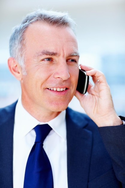 Executive discussing business deal Man in suit smiling while talking on cell phone