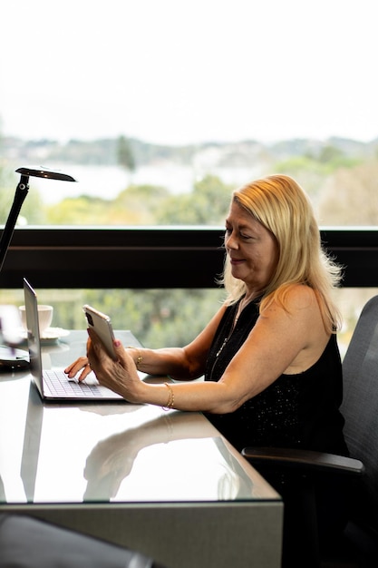 executive lady in her home office making a video conference by cell phone